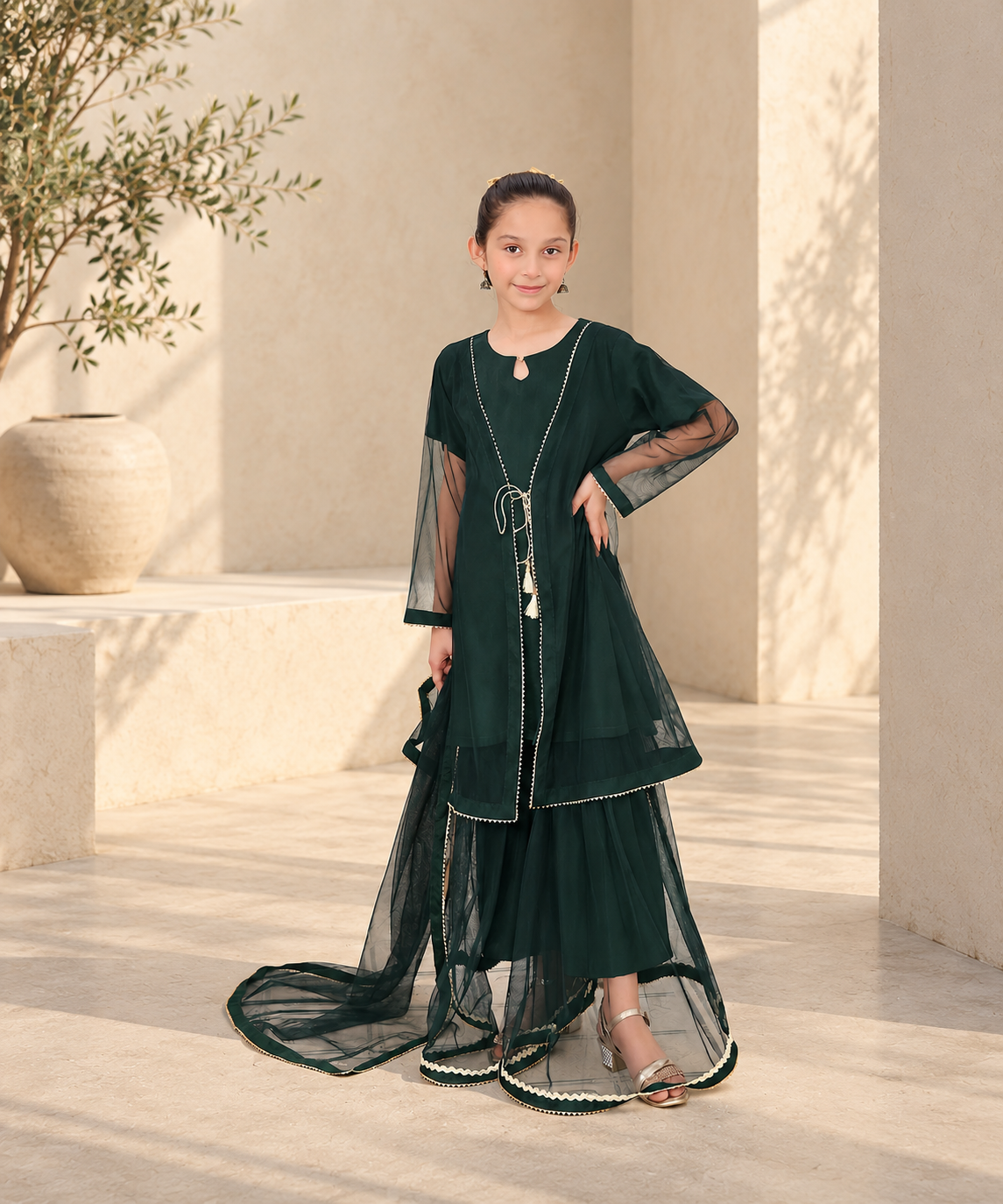 Girl wearing a green three-piece outfit in a sunlit courtyard.