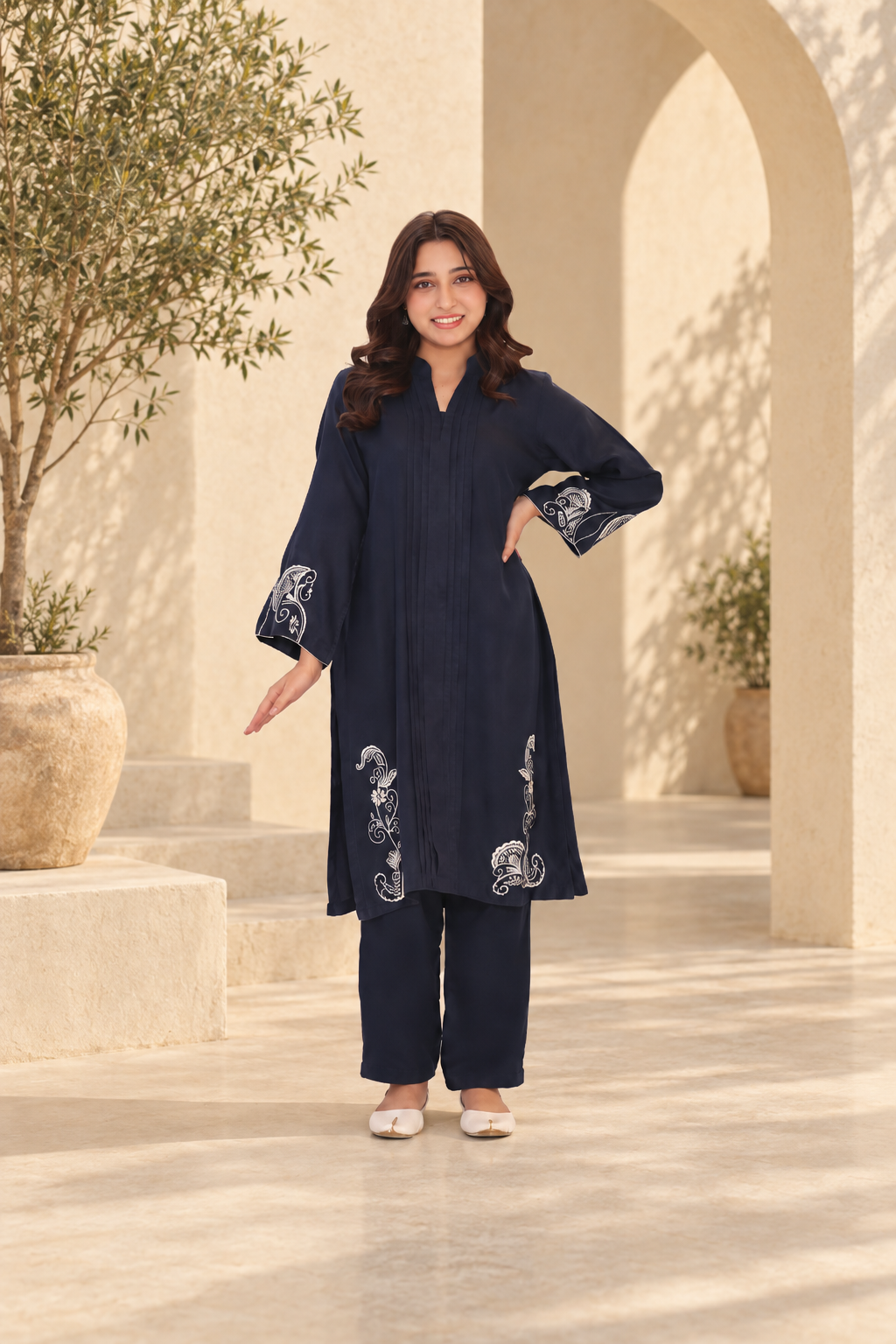 Navy embroidered outfit in a sunlit courtyard.