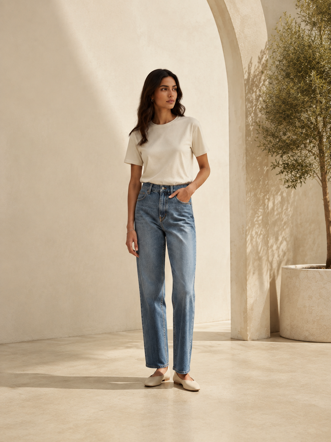 A woman wearing an ivory T-shirt and blue jeans.